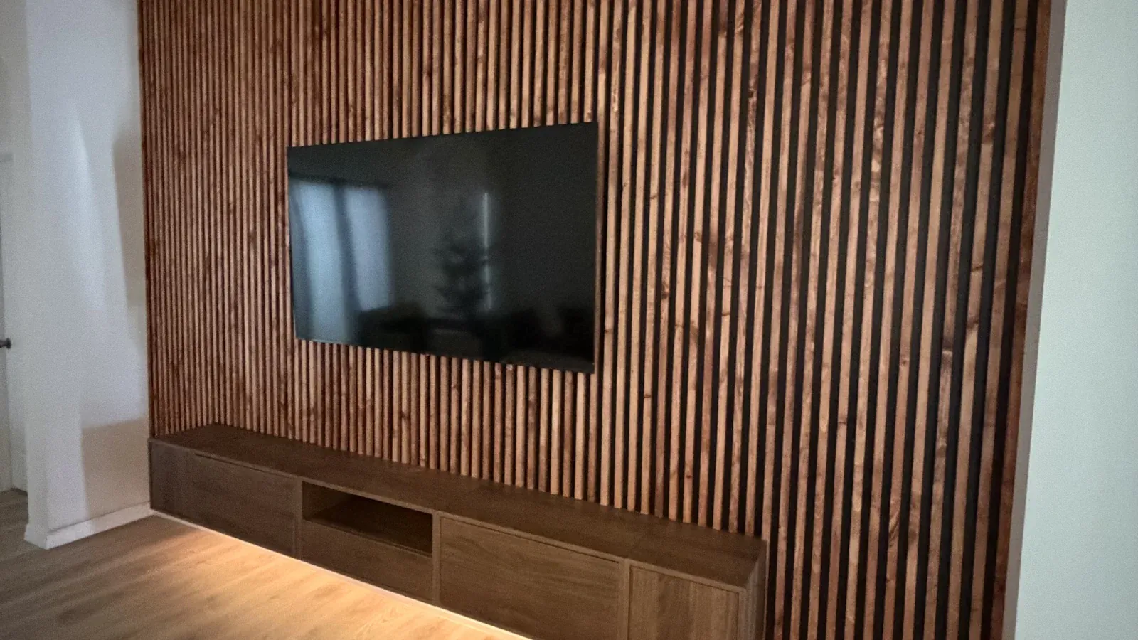 The same wall finished as a wood slat media wall