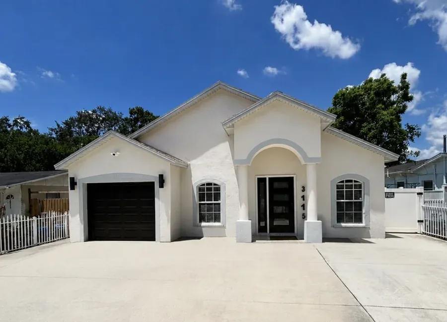 Stucco home exterior repainted in a crisp white with dark trim