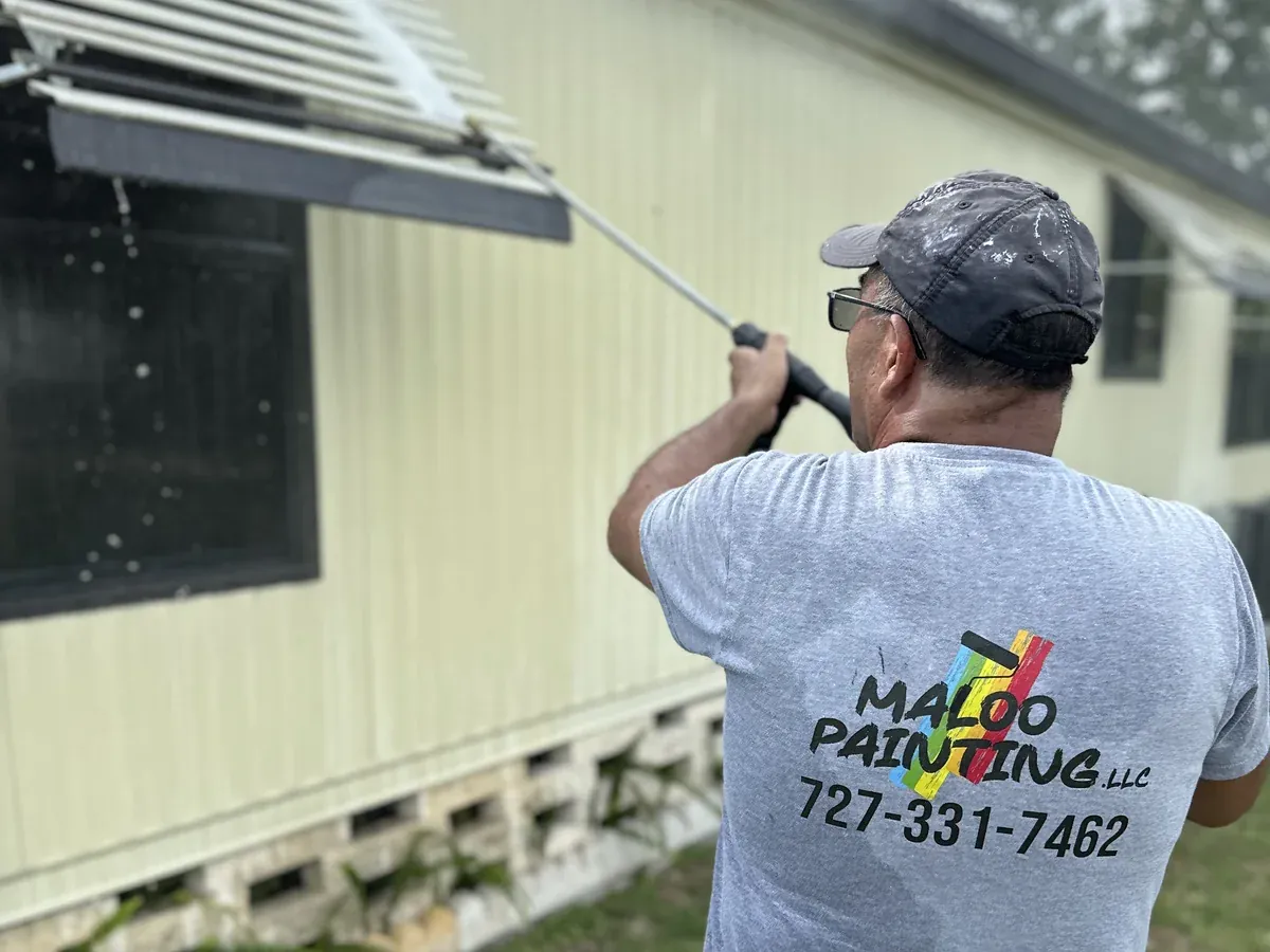 A Maloo Painting crew member soft-washing the side of a house